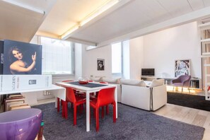 A modern living space with a dining area, a sofa, and a TV. - Fori Imperiali Hi Tech Apartment (Roma)