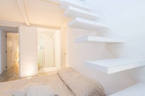 A room with a bed, a door leading to a bathroom, and white built-in shelves. - Fori Imperiali Hi Tech Apartment (Roma)