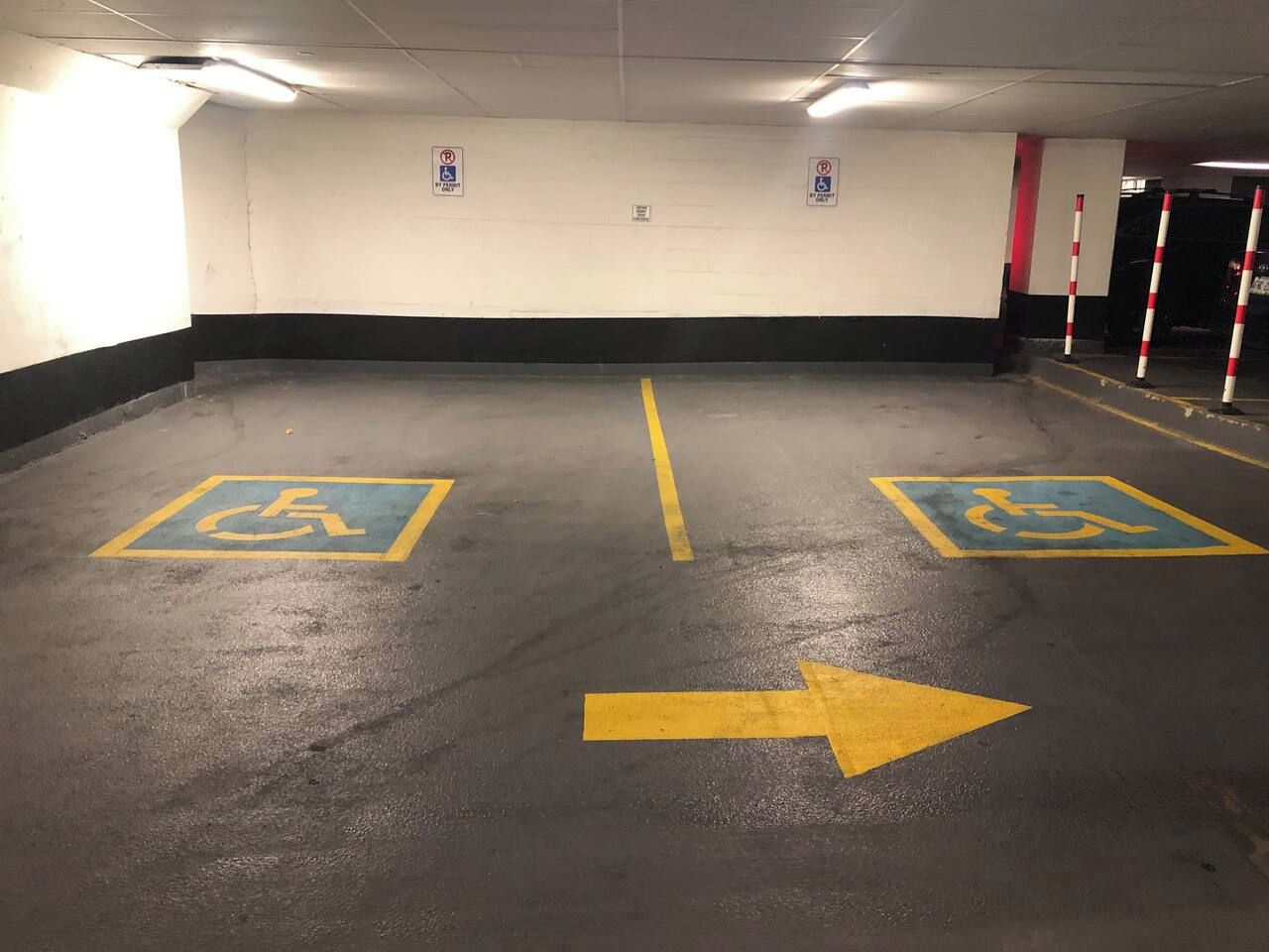 A parking garage with two handicapped parking spaces marked with blue and yellow paint.