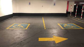 A parking garage with two handicapped parking spaces marked with blue and yellow paint.