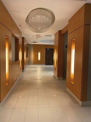 A hotel corridor with wooden paneling, recessed lighting, and a circular ceiling feature. - Urban Furnished 1-BR | GTA Skyline views | Casino (Toronto)