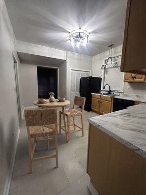 A compact kitchen with a dining area, featuring a round table, two chairs, a refrigerator, and a sink. - Spacious 3-bedroom condo in Lake View, Chicago (Chicago)