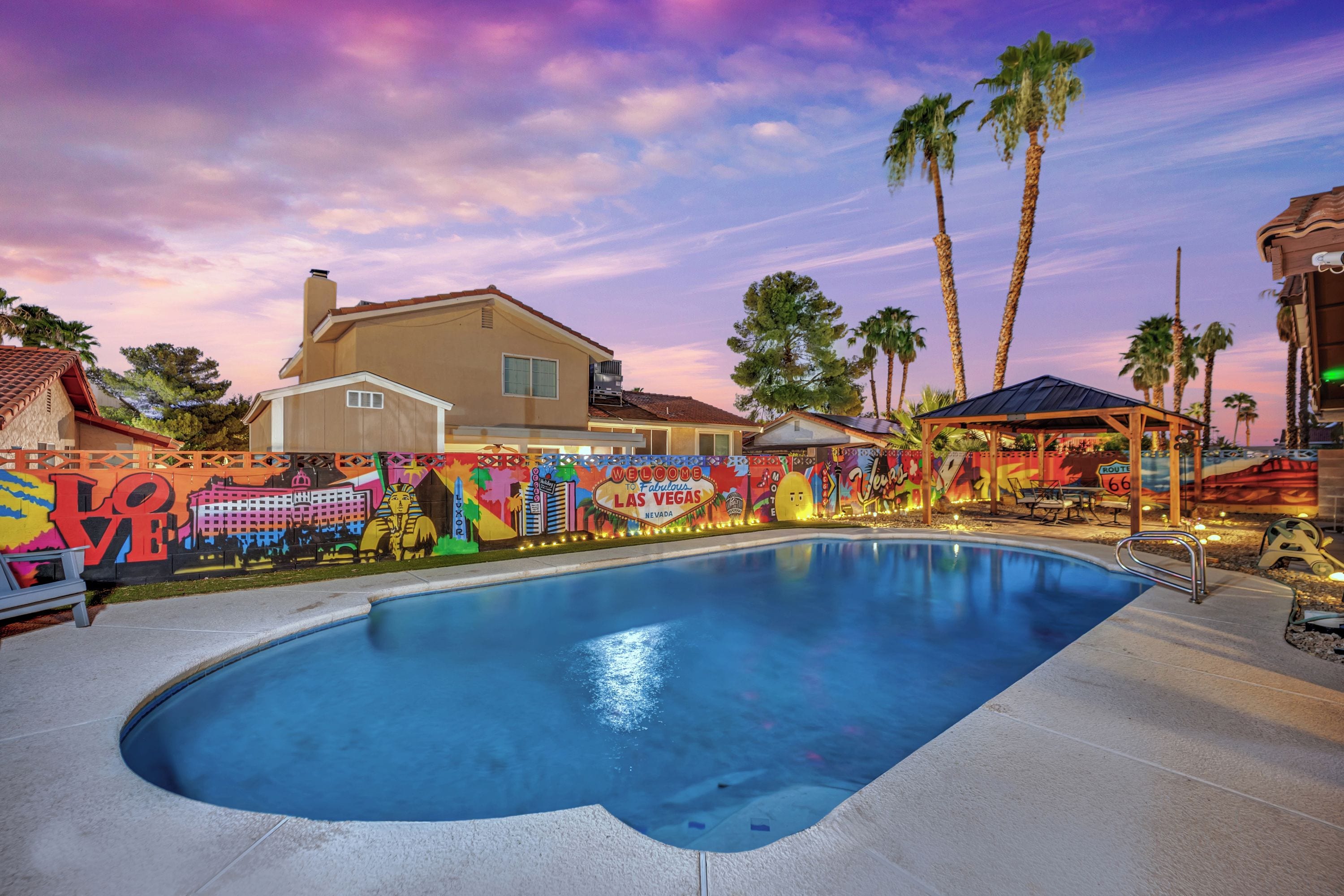 A swimming pool with a colorful mural and palm trees in the background.