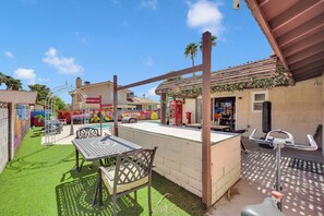A pool area with a table and chairs, a pergola, and a red telephone booth. - Vegas Angel • Pool, Arcade Room & Strip Views (Las Vegas)