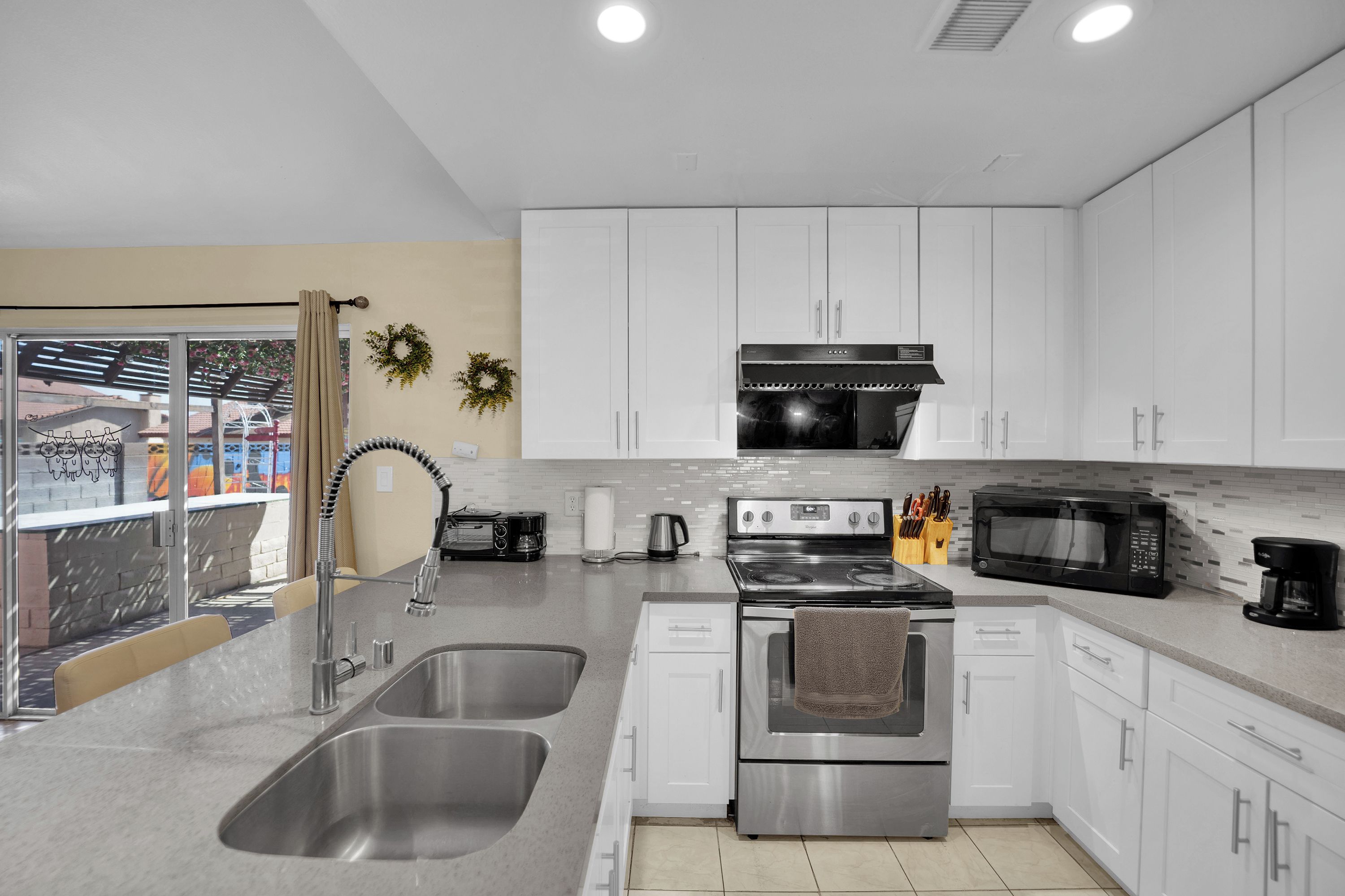 A modern kitchen with stainless steel appliances, white cabinetry, and a double sink.