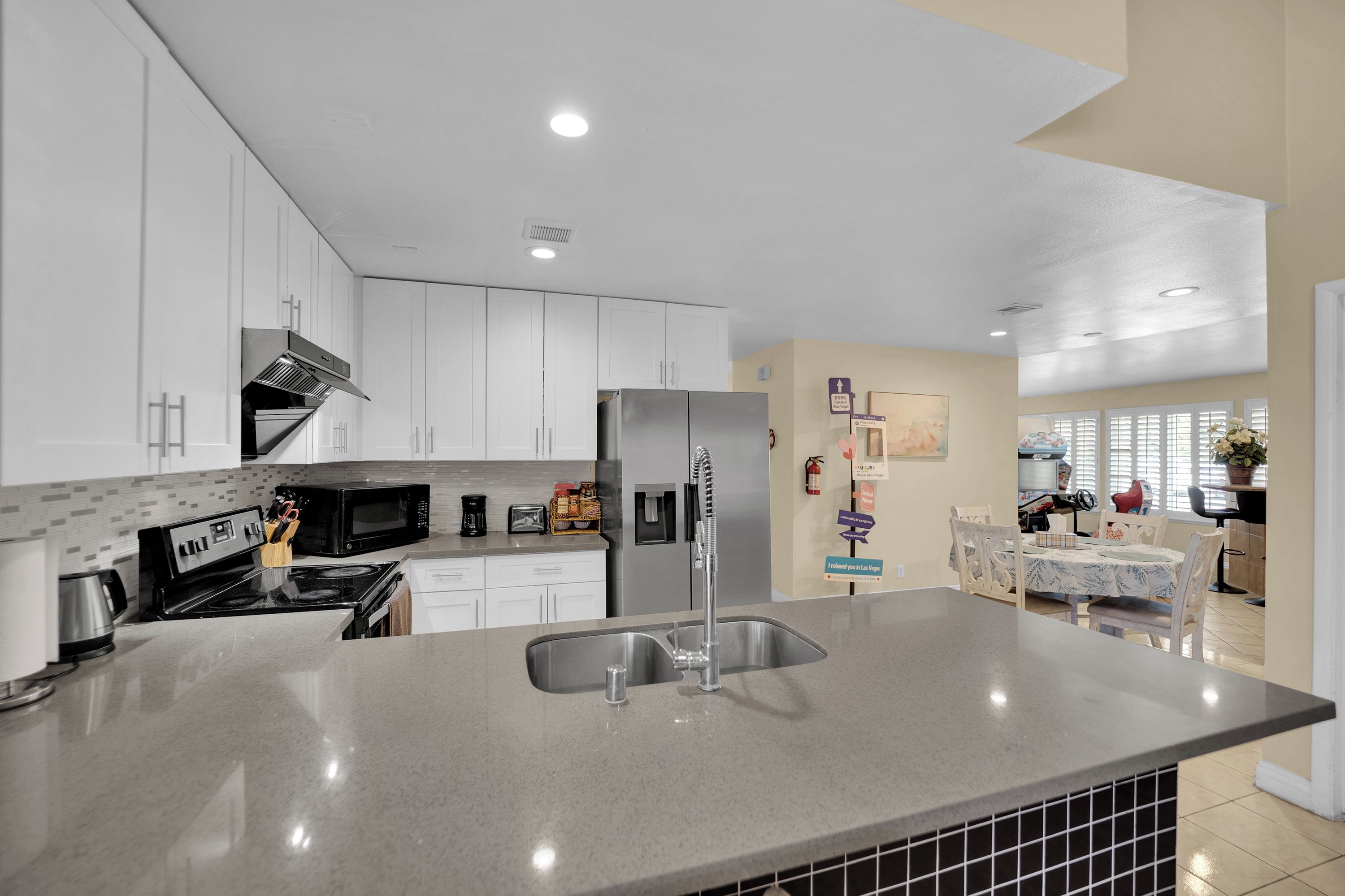 A modern kitchen with white cabinets, a stainless steel refrigerator, and a granite countertop.