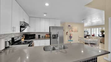 A modern kitchen with white cabinets, a stainless steel refrigerator, and a granite countertop.