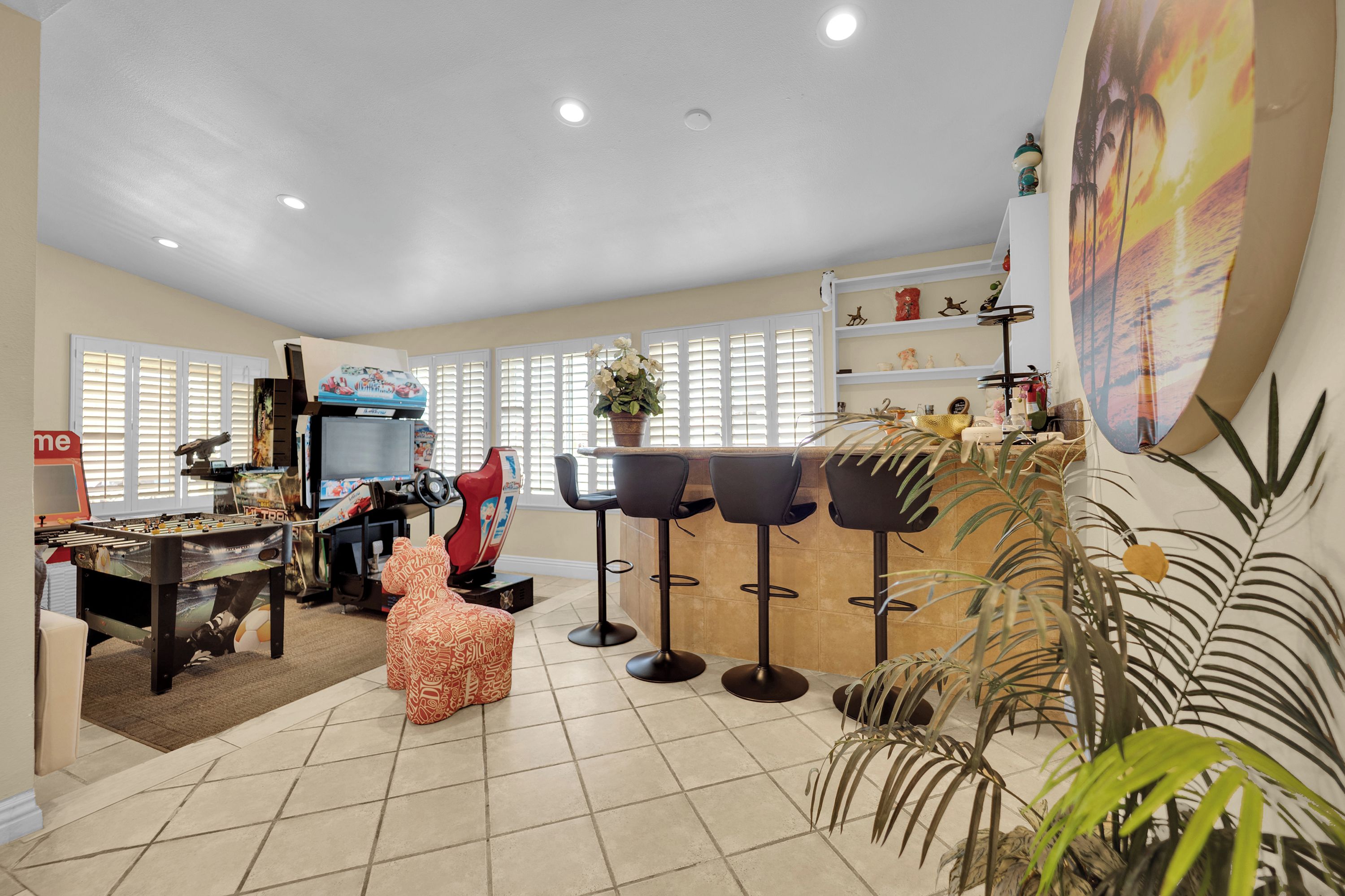 A spacious living area with a foosball table, a television, and a bar area with stools.