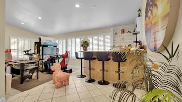 A spacious living area with a foosball table, a television, and a bar area with stools.