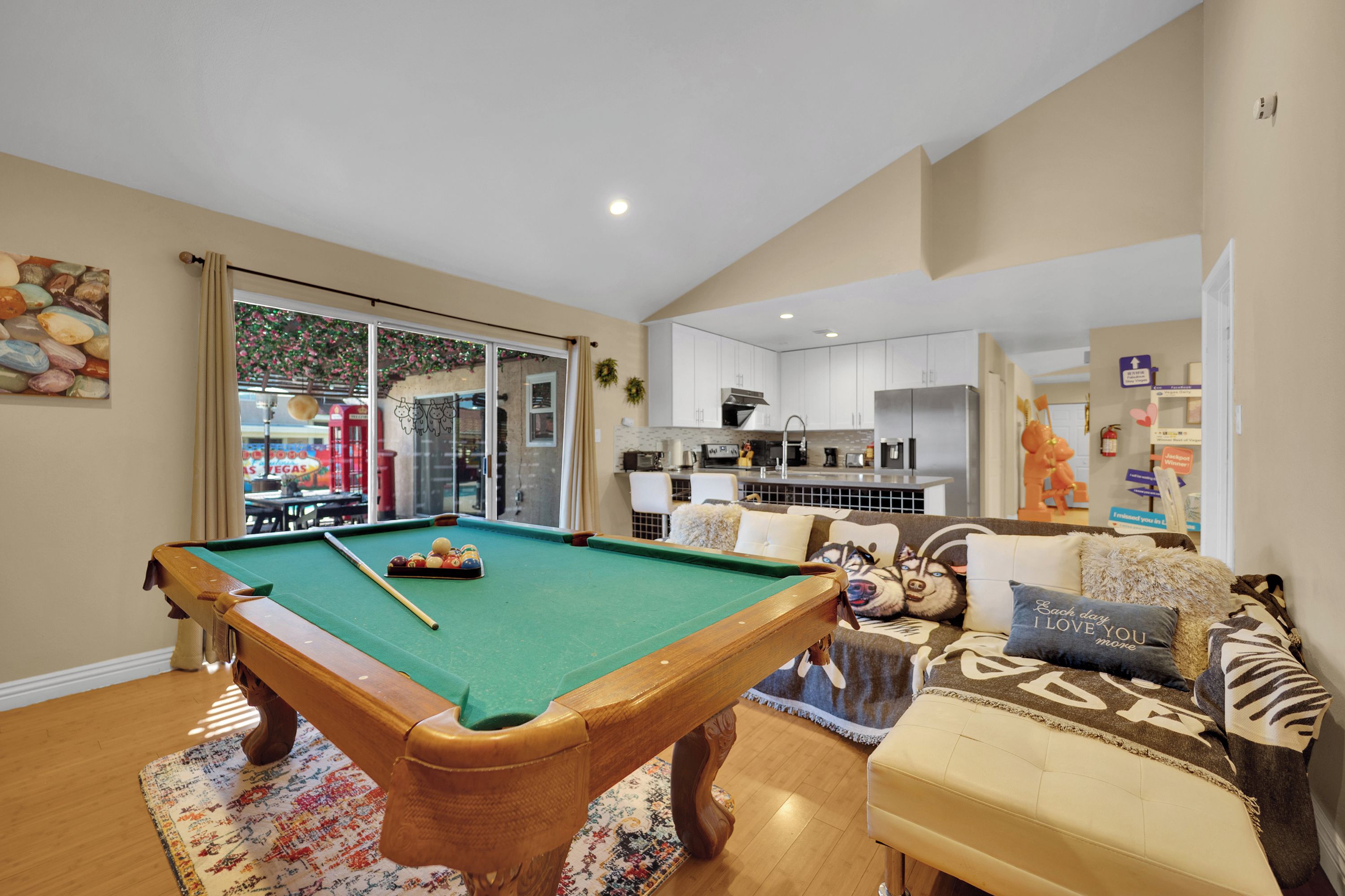 A pool table in a living room with a view of a casino through the window.