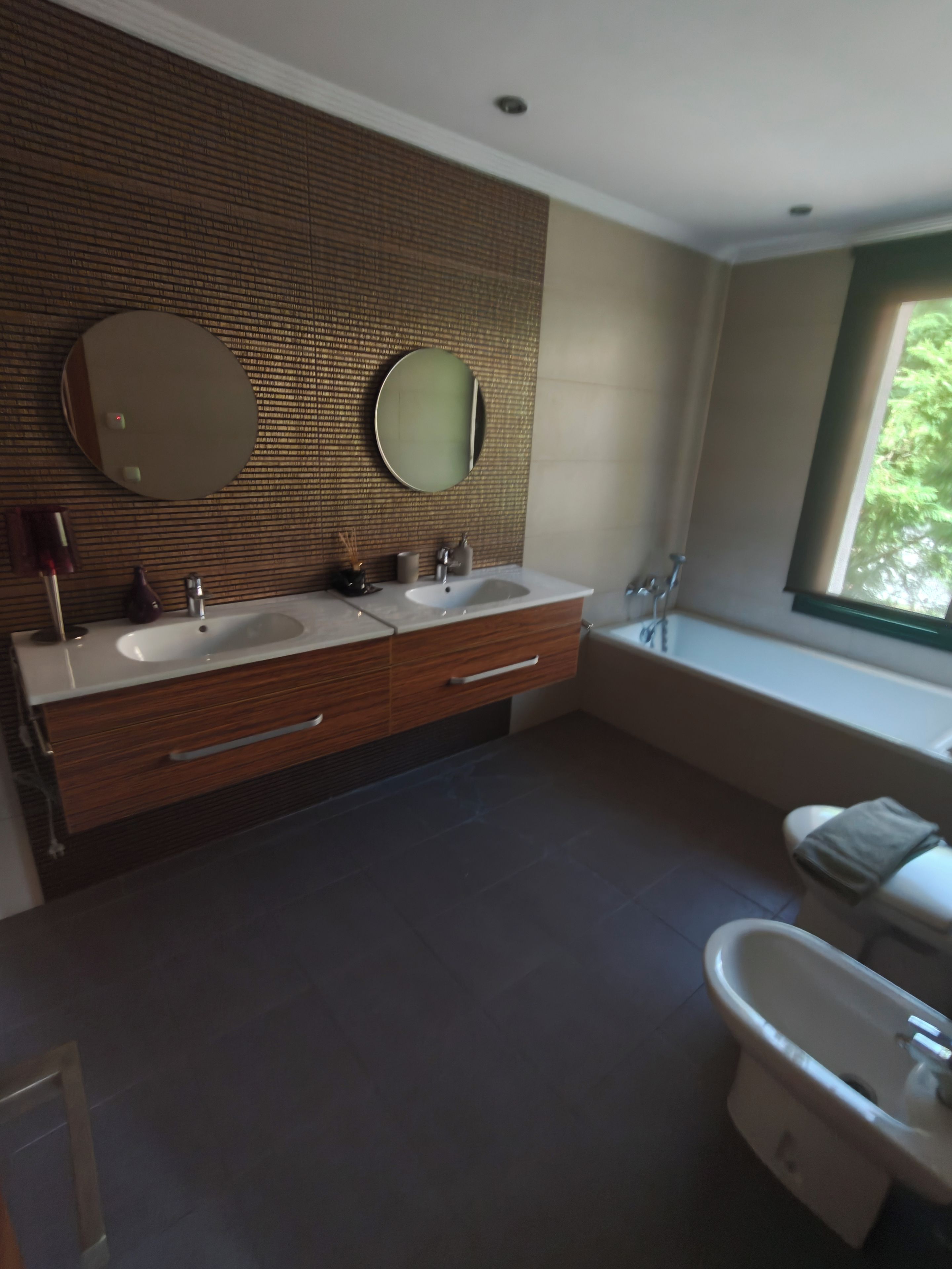 A modern bathroom with two sinks, a large mirror, and a bathtub.