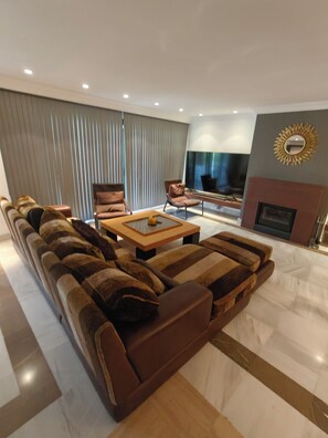 Een moderne woonkamer met een hoekbank, een salontafel en een flatscreen televisie.