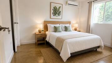 Un dormitorio con cama, mesitas de noche, ventilador de techo, aire acondicionado y ventana con cortinas.