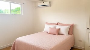 Een slaapkamer met een bed, een raam en een airconditioning.