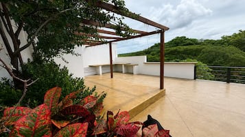 Terraza en la azotea con pérgola, zona de estar y vistas a zonas verdes.