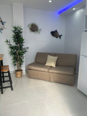 A living room with a sofa, a small table, a chair, a potted plant, and wall decorations. - Caribe House, just 7 minutes from the San Juan airport, close to everything (Carolina)