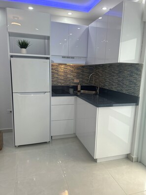A modern kitchen with white cabinetry, a black countertop, and a backsplash with a brick pattern. - Caribe House, just 7 minutes from the San Juan airport, close to everything (Carolina)
