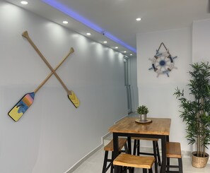 A modern dining area with a wooden table and benches, a wall-mounted paddle, a decorative ship's wheel, and a potted plant. - Caribe House, just 7 minutes from the San Juan airport, close to everything (Carolina)