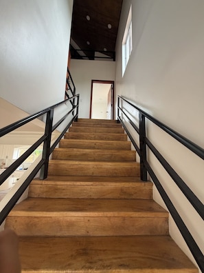 A wooden staircase with black railings leading to a door at the top. - Horizonte Apartment: Nature and Pool (Sucio (San Juan del Sur))