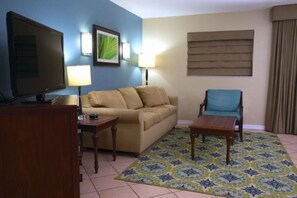 A living room with a television, a sofa, a chair, a coffee table, and a patterned rug. - Pompano Beach | Pool & Golf Access | Coastal Escape Stay (Pompano Beach)