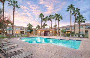 A hotel with a swimming pool, palm trees, and a covered area with lounge chairs. - Palm Springs | Easy Access Studio Stay | Pool + Spa (Cathedral City)