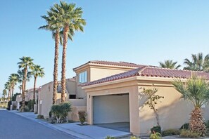 A residential building with a tiled roof, a garage, and palm trees.