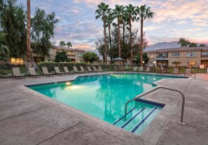A swimming pool with lounge chairs and palm trees, surrounded by buildings. - Palm Springs | Easy Access Studio Stay | Pool + Spa (Cathedral City)