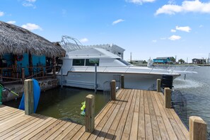 A yacht docked at a pier with a thatched-roof building nearby. - The Black Pearl Dry Docked Studio Boat Room (Bay City)