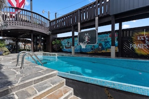 A swimming pool with a stone deck and a mural on the adjacent wall. - The Black Pearl Dry Docked Studio Boat Room (Bay City)