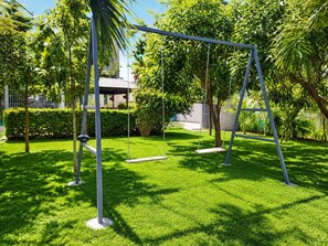 Ein gepflegter Garten mit Schaukel, ordentlich geschnittenem Rasen und verschiedenen Bäumen.
