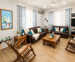Una sala de estar con dos sofás de cuero marrón, una mesa de centro de madera, un sillón mecededor de madera y un tablero de ajedrez.