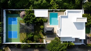 Ein Luftbild eines Anwesens mit Tennisplatz, Schwimmbad und überdachter Terrasse.