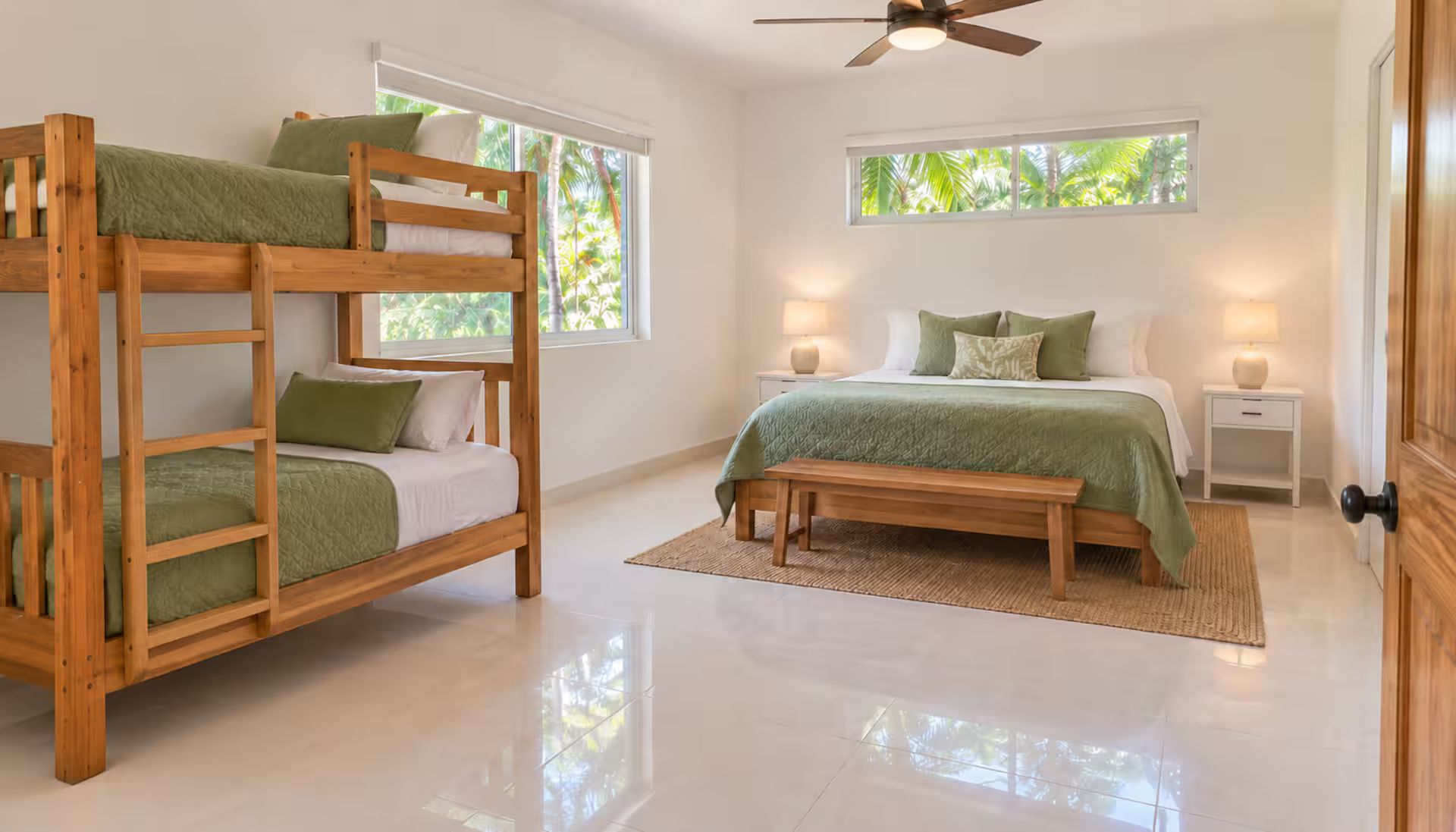 A bedroom with bunk beds, a single bed, a ceiling fan, and a view of greenery through the windows.