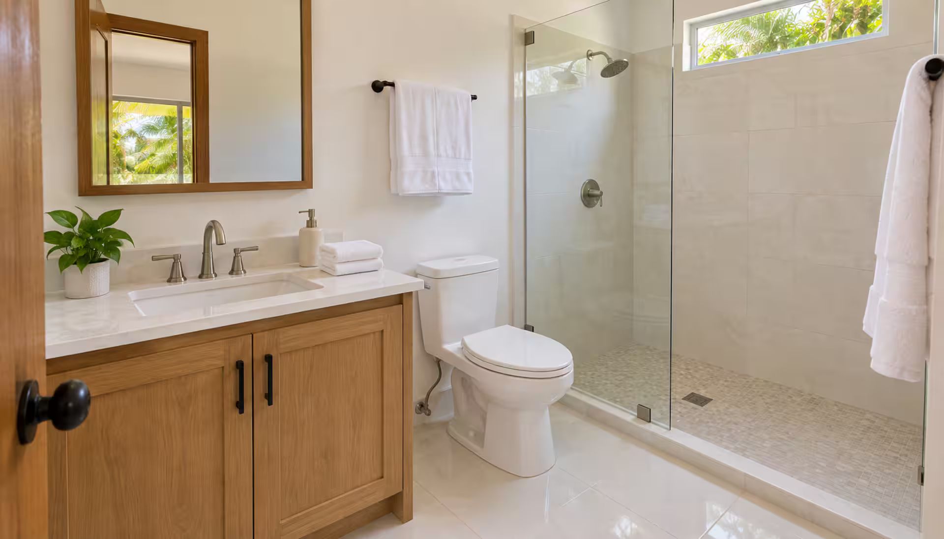 A bathroom with a wooden vanity, a white sink, a toilet, and a glass-enclosed shower area.