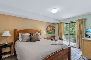 A hotel room with a large bed, a painting on the wall, a window with curtains, and a television on a wooden cabinet. - Okemo Ski Escape | Steps to the Slopes (Ludlow)