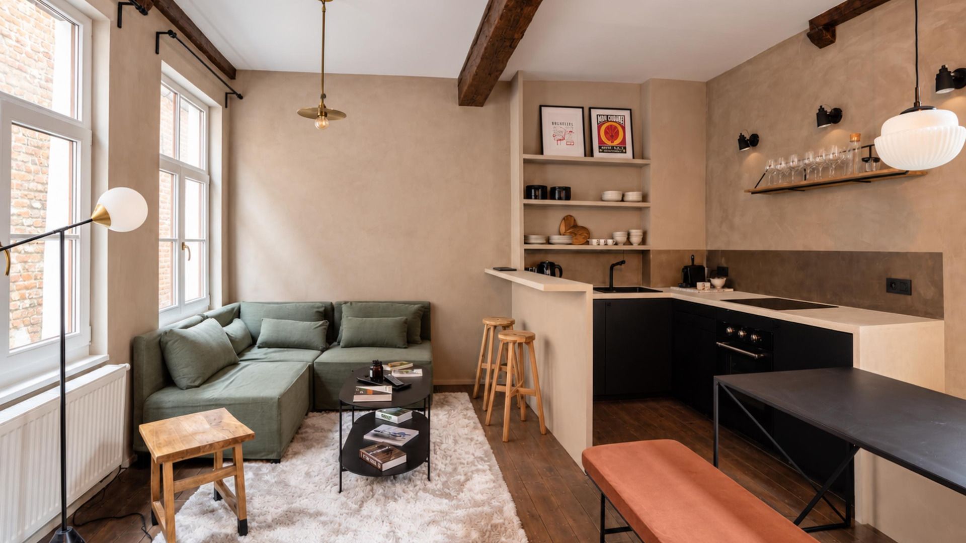 A compact living space with a sofa, a small coffee table, a bench, a kitchen area with a sink and cabinets, and a dining table.