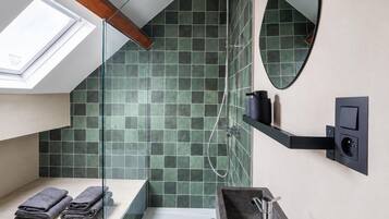 Een moderne badkamer met dakraam, douche, wastafel en spiegel.