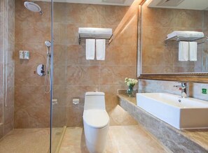 Ein modernes Badezimmer mit einer Duschkabine, einer weißen Toilette und einem großen Waschbecken mit Spiegel darüber.