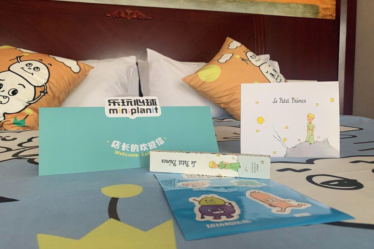 Een bed met een bedovertrek met patroon, kussens met tekenfilmfiguren en verschillende wenskaarten.