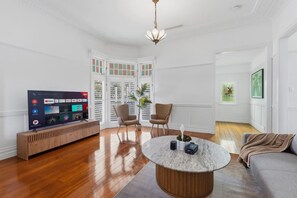 Ein Wohnzimmer mit Flachbildfernseher, zwei Sesseln, einem Couchtisch und einer Couch.