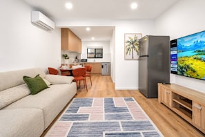A modern living room with a sofa, a coffee table, and a TV on a wooden cabinet. - Brand-New 2B |Walk to Beach & Cavill Ave |Full A/C (Surfers Paradise)