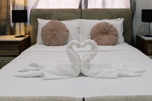 A neatly made bed with a heart-shaped towel arrangement in the center, two round pillows, and a headboard. - Family Retreat |Private Pool|Multi Living|Full AC (Forestdale)