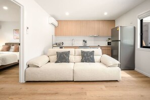Ein kompakter Wohnbereich mit einer Couch, einer Küchenzeile und einem Kühlschrank.