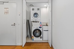 Ett tvättrum med en tvättmaskin med frontmatning, en torktumlare och ett litet handfat.