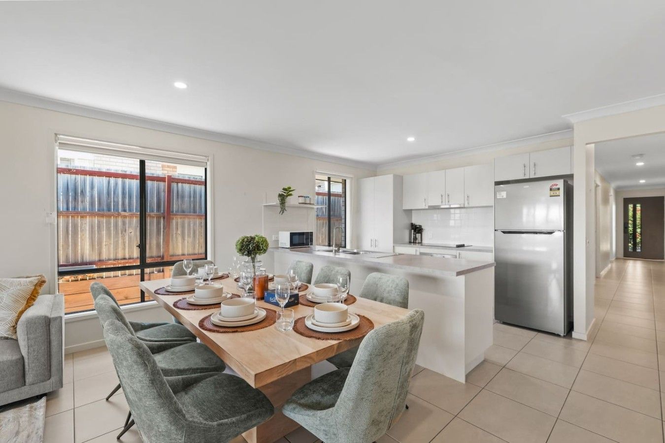 A modern kitchen with a central island, white cabinetry, and a stainless steel refrigerator.