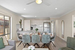 Un espace de salle à manger moderne, avec une table dressée pour quatre personnes, entourée de chaises grises à revêtement rembourré et aux pieds noirs.