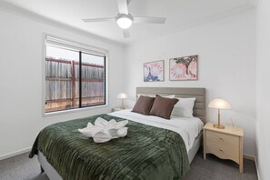 Une chambre à coucher avec un lit, une fenêtre donnant sur un beau paysage, un ventilateur de plafond et deux lampes fixées au mur.