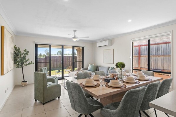 Un coin repas avec une table dressée pour six personnes, entourée de chaises grises à revêtement rembourré.