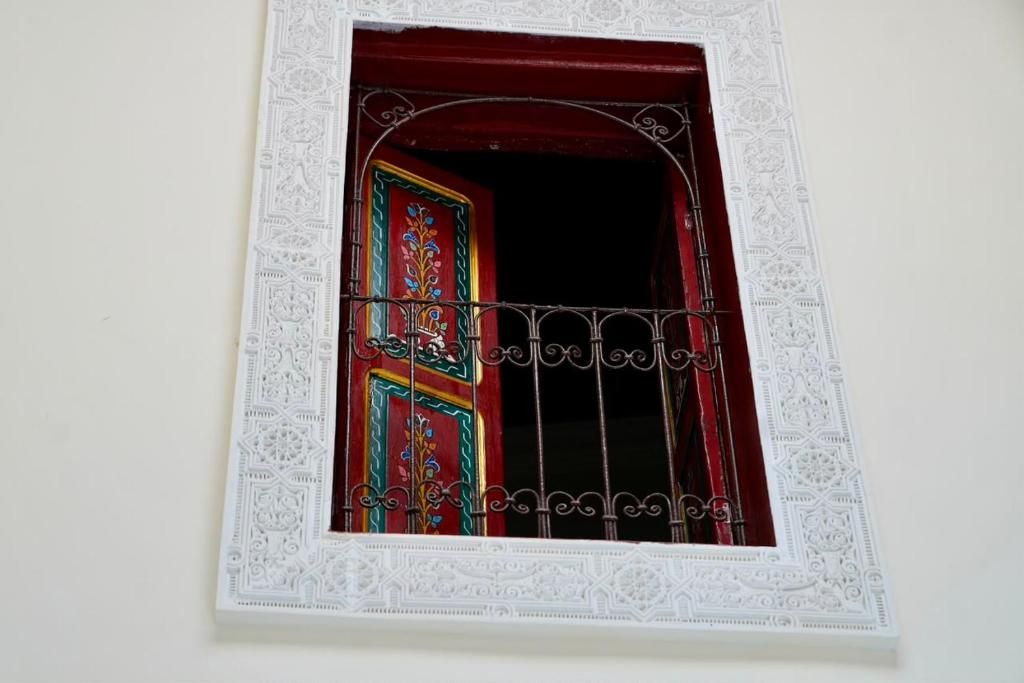 Una ventana con detallado marco blanco y una puerta decorativa con diseño rojo y verde.