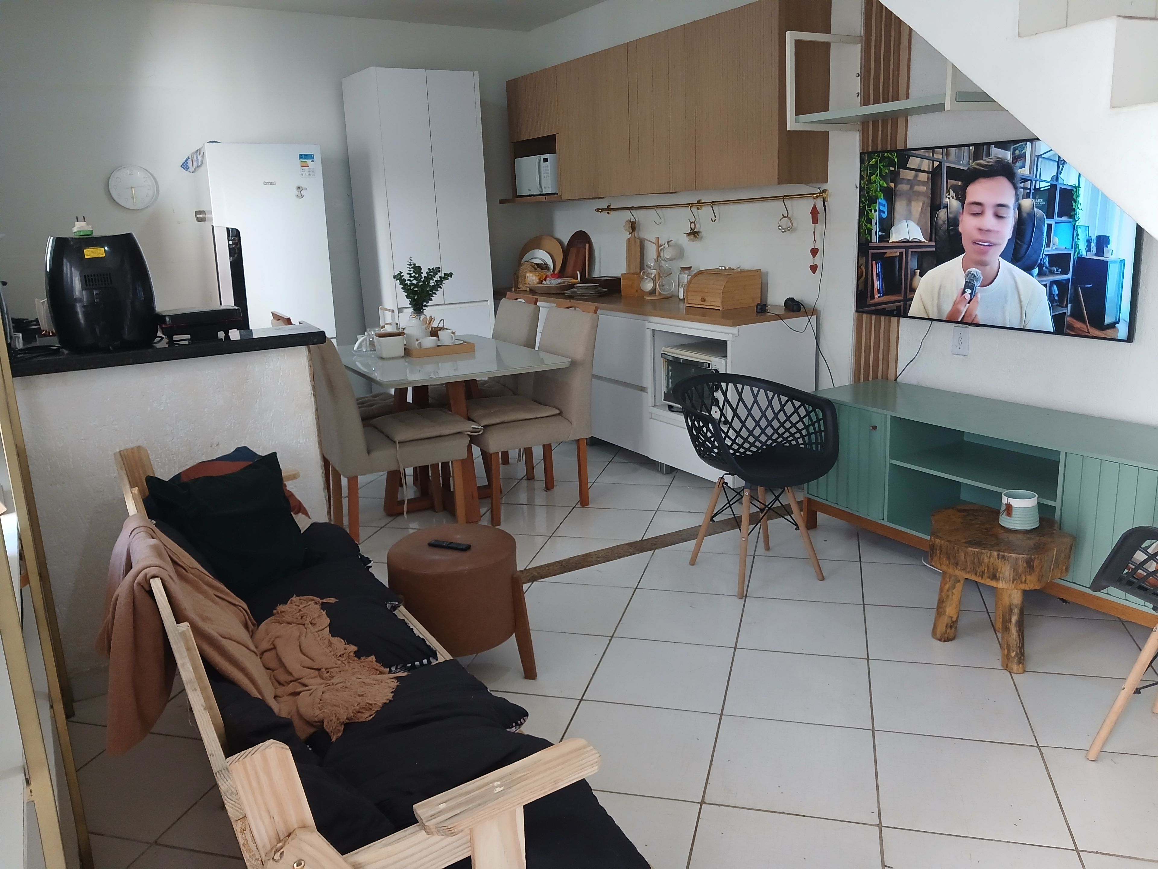 Un espacio habitable compacto con kitchenette, comedor y zona de estar con sofá y sillón.